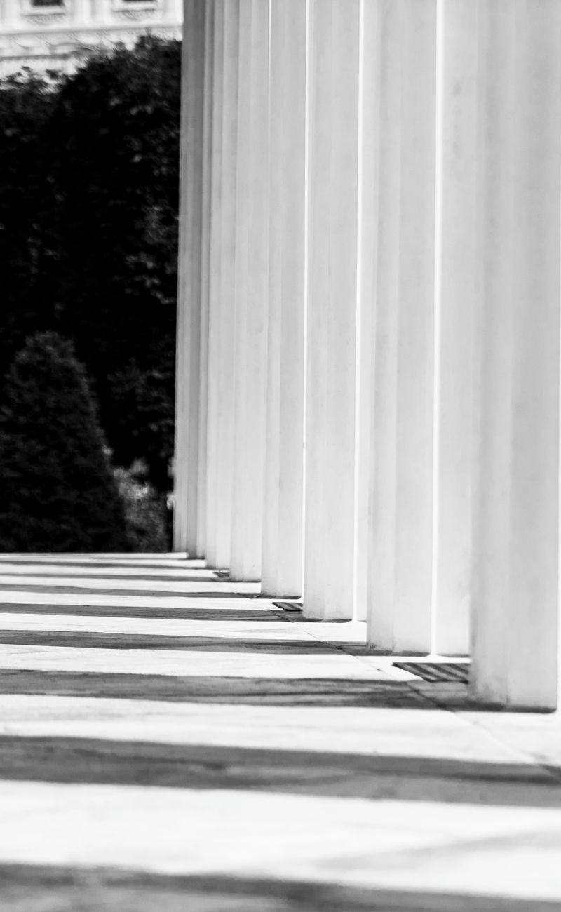 Classical stone columns and a shaded walkway in black and white