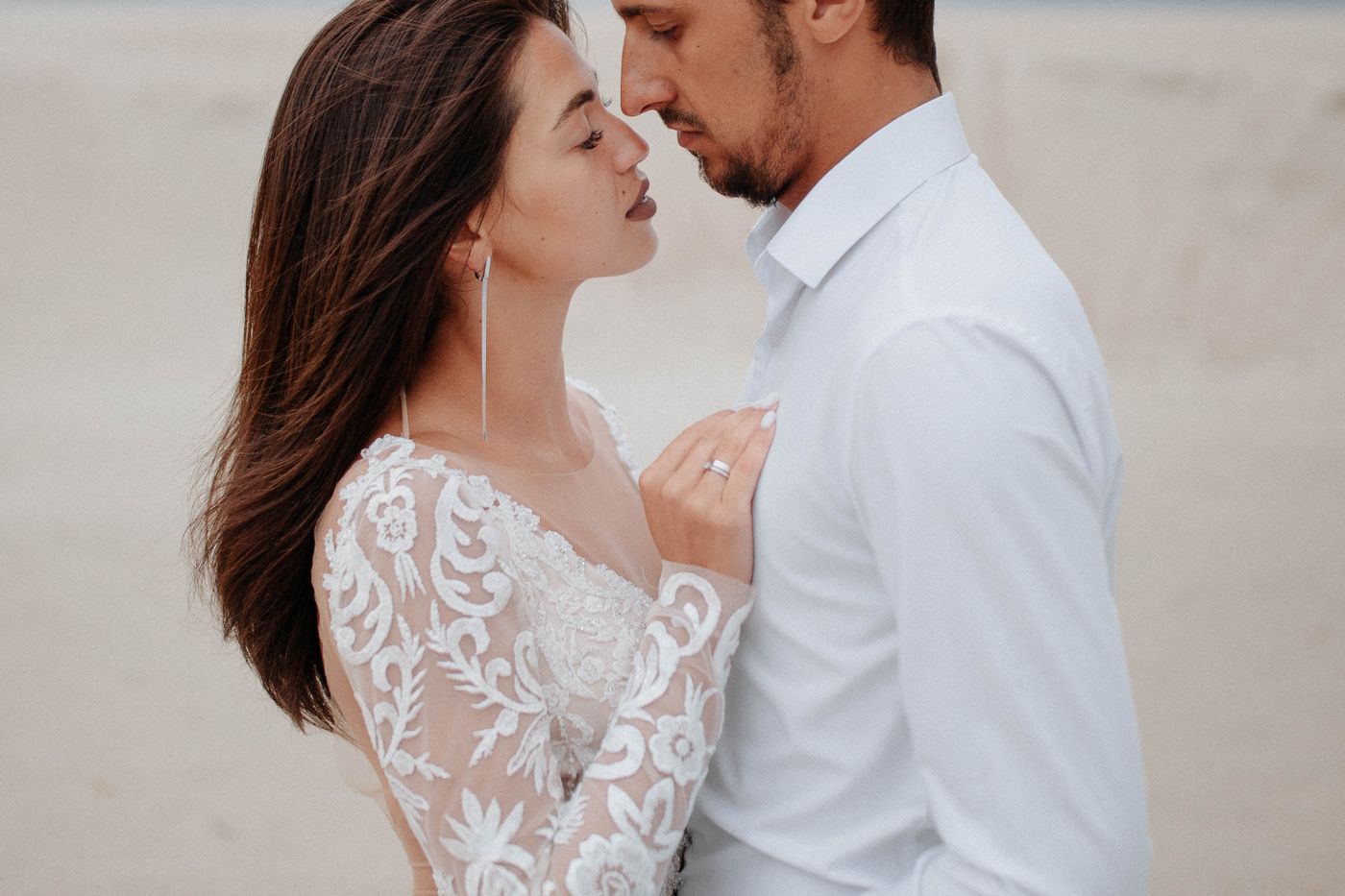 Couple forehead to forehead in soft light, lace sleeve and white shirt