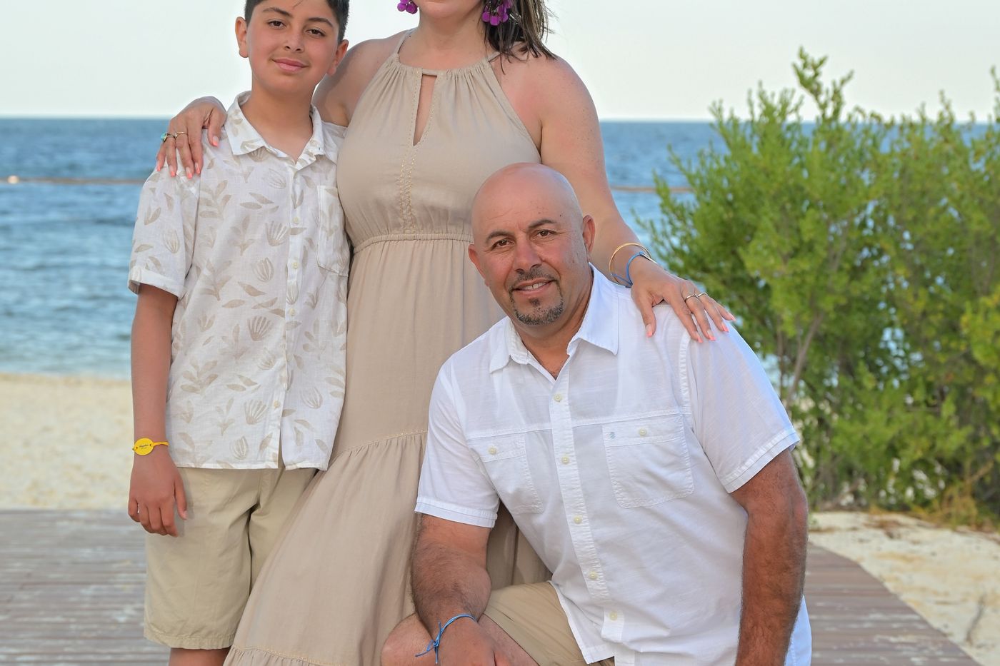 Family of four in white and tan on a boardwalk by the water