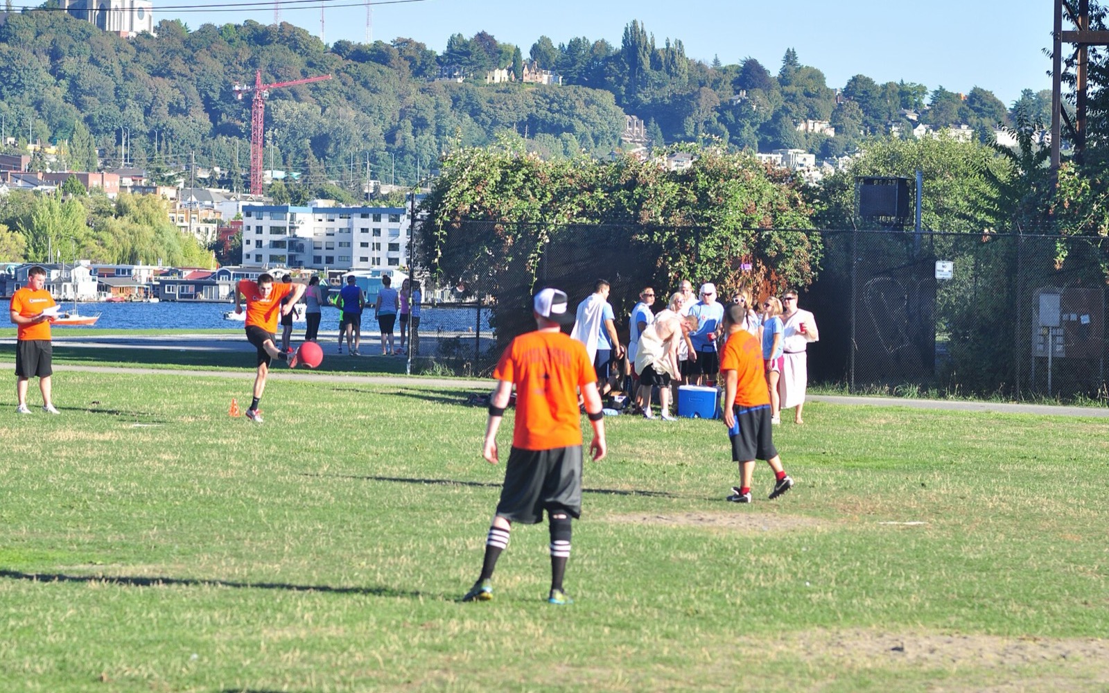 Players in orange socks chasing a ball across green turf