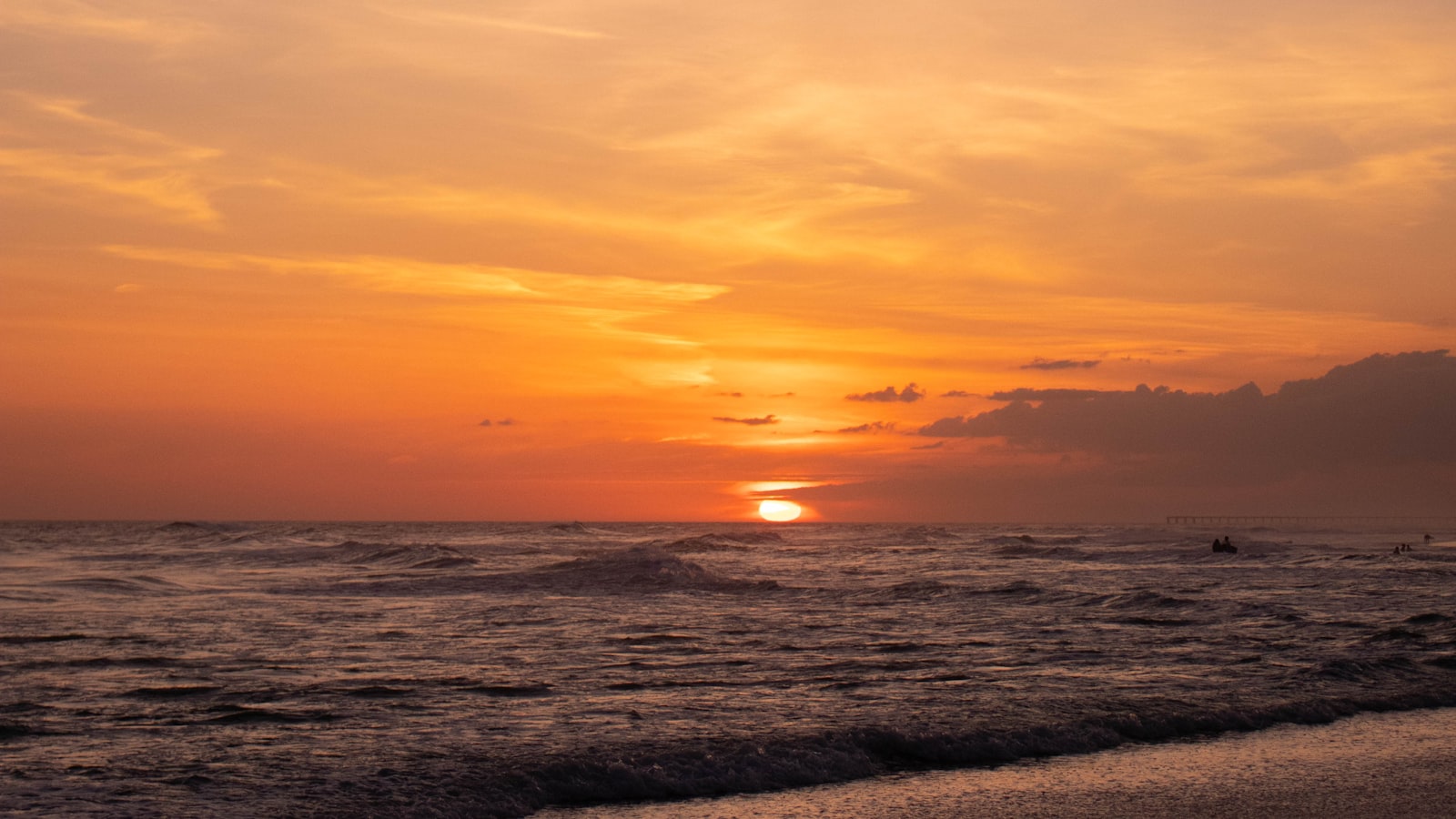 An orange sunset over calm Gulf water