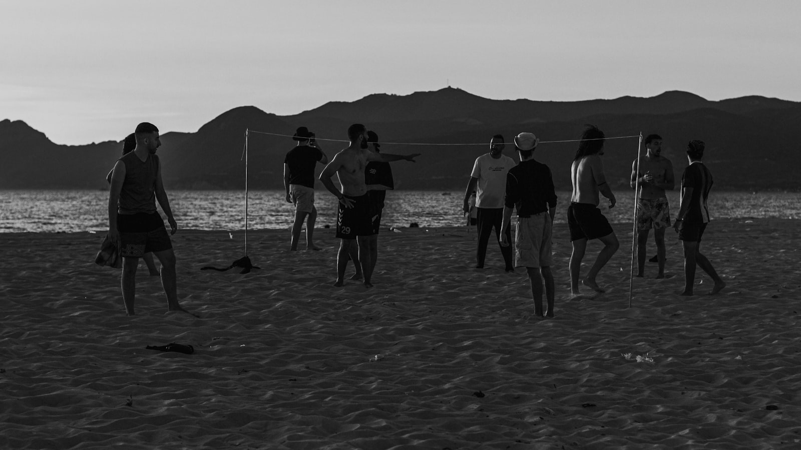 Silhouettes of friends playing beach volleyball at dusk